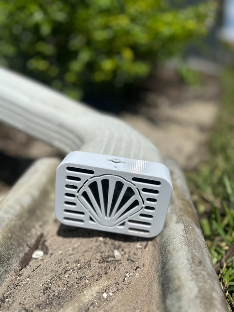Seashell decorative gutter cap installed on beach home downspout, ocean-themed exterior accent by Coastal Spouts.